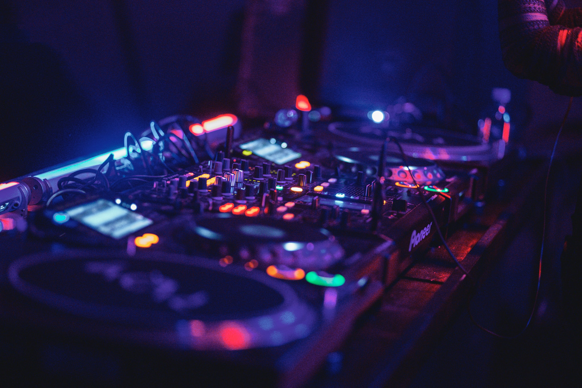 Pioneer DJ decks and mixer lit in blue and red, jog wheels and cue buttons glowing.